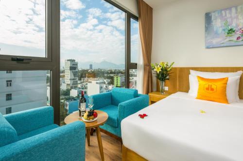 una camera d'albergo con un letto, sedie e una finestra di Cordial Hotel and Spa a Da Nang