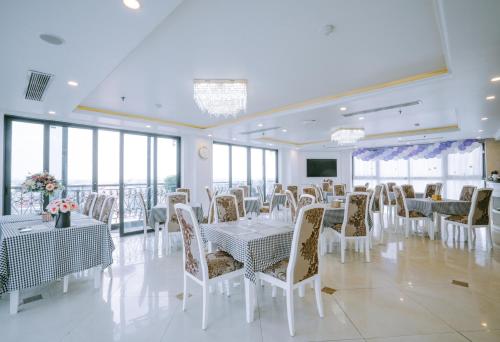 a banquet hall with white tables and chairs and windows at GM Hotel and Apartment in Hai Phong