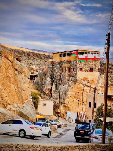 a train on the side of a mountain with parked cars at Hissen Al-Misfah in Misfāh