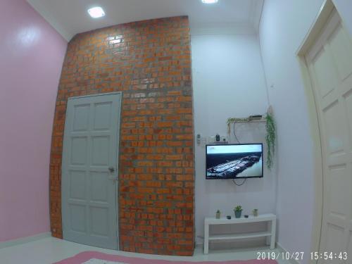 a brick wall with a door and a tv on a wall at Holiday Homestay Dungun in Dungun