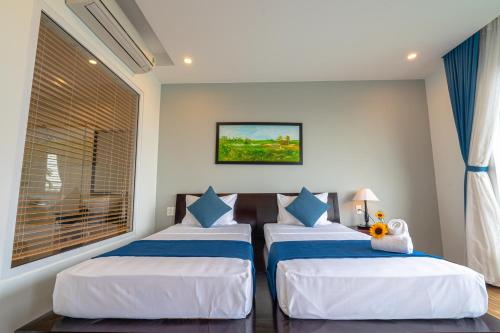 a bedroom with three beds with blue and white pillows at Golden Star Villa Hoi An in Hoi An