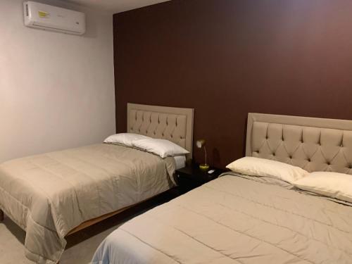 2 camas en una habitación de hotel con 2 colchas en LOMAS SUITES, en Ciudad Valles