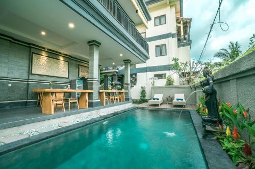 a house with a swimming pool with a table at Three Dewi's Guest House in Ubud