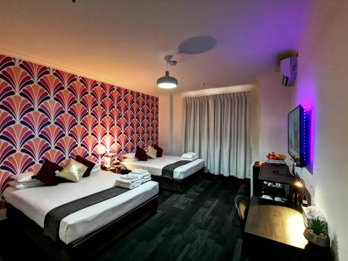 een hotelkamer met 2 bedden en een televisie bij Criterion Hotel Perth in Perth