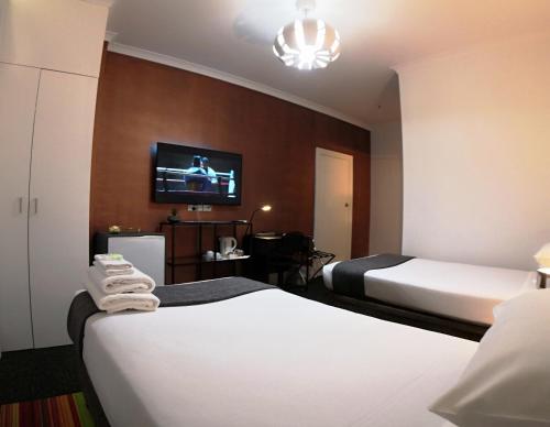 a hotel room with two beds and a flat screen tv at Criterion Hotel Perth in Perth