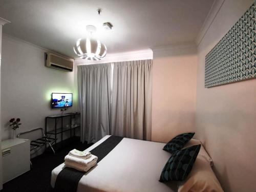 a bedroom with a large bed and a chandelier at Criterion Hotel Perth in Perth