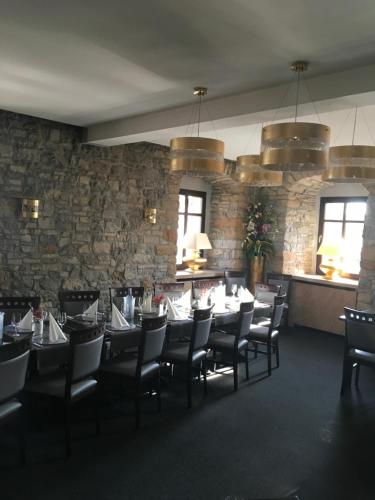 Pension Gasthaus Zur Forelle في Seeburg: غرفة طعام بها طاولات وكراسي وجدار حجري