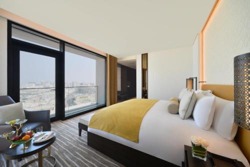 a hotel room with a bed and a large window at Alwadi Hotel Doha - MGallery Collection in Doha