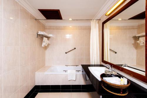 a bathroom with a tub and a sink and a mirror at Steung Siemreap Hotel in Siem Reap