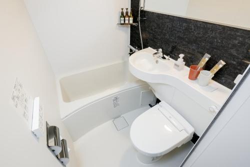 een witte badkamer met een toilet en een wastafel bij M's Hotel Kyoto Station Kizuya in Kyoto