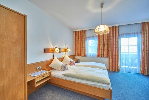 Schlafzimmer mit einem großen Bett, einem Schreibtisch und einer Lampe in der Unterkunft Hotel Gasthof Schweizerhaus in Stuhlfelden