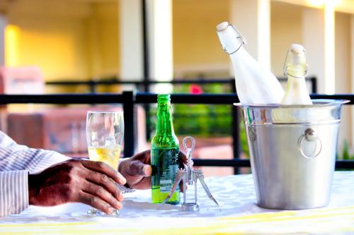 a person sitting at a table with a bottle and a glass at Pits Lodge in Polokwane