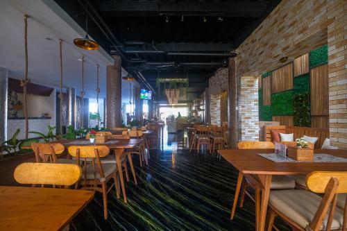 un restaurant avec des tables et des chaises en bois et des murs en briques dans l'établissement Papillon Echo Beach, à Canggu