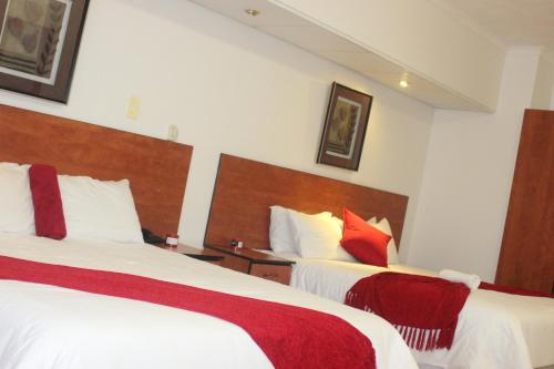 a hotel room with two beds with white and red pillows at Pits Lodge in Polokwane
