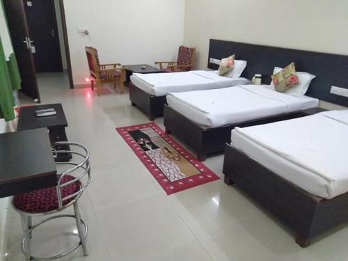 a room with four beds and a table and chairs at Hotel the Ideal in Kushinagar