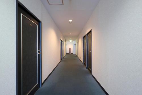 an empty corridor with doors and a long hallway at Tabist Izumi Yusen Shukuhaku Center in Izumi
