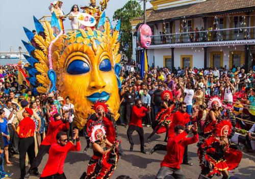 a group of people in a parade with a giant mask at Time & Leisure Hotels in Candolim