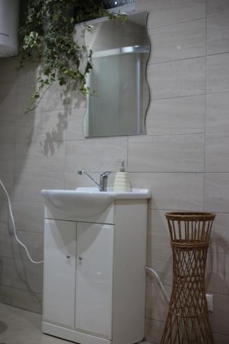 y baño con lavabo blanco y espejo. en Apartmany Fantagiro, en Kaluža