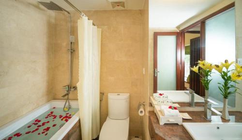 a bathroom with a tub and a toilet and a sink at Elites Riverside Hotel & Spa Hoi An in Hoi An