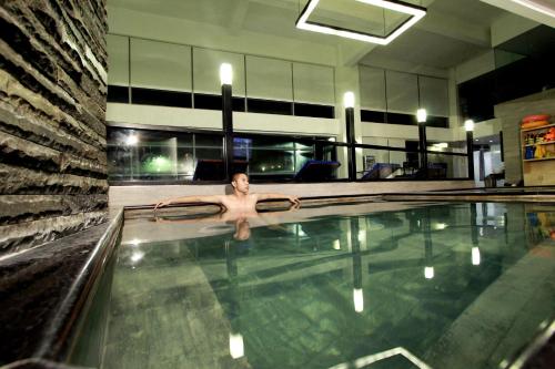 a man in a swimming pool in a building at Forbis Hotel in Serang
