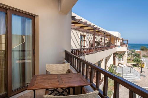 a balcony with a wooden table and chairs at Indigo Mare in Plataniás