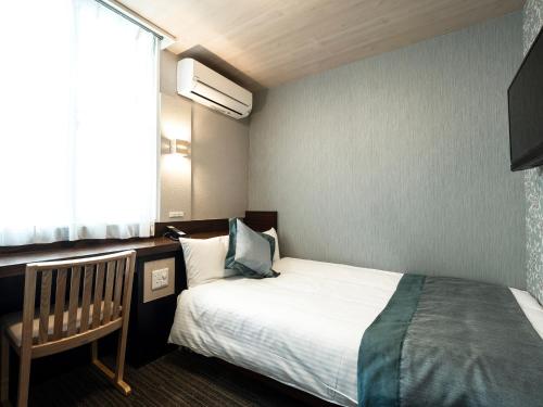 a small bedroom with a bed and a window at Hotel AreaOne Izumo in Izumo