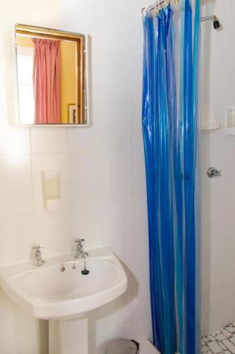 a bathroom with a sink and a blue shower curtain at Fernando's the Grange in Port Elizabeth