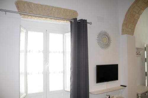 a room with a window with a curtain and a tv at CASA ARCO DEL CAÑÓN - Casita con Encanto in Medina Sidonia