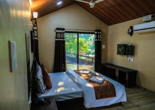 a bedroom with a bed and a window with a view at Coconut Beach Farm in Alibaug