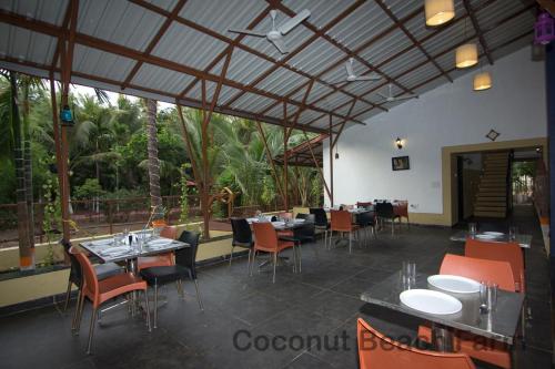 a restaurant with tables and chairs and a large window at Coconut Beach Farm in Alibaug