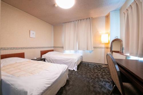 a hotel room with two beds and a desk at Grand Hotel Seifuso in Ōmuta