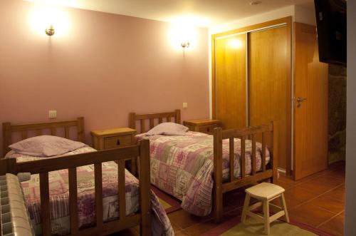 a bedroom with two beds and a door to a bathroom at Casa Fonte Do Laboreiro in Castro Laboreiro