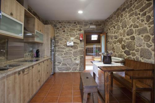 a kitchen with wooden cabinets and a stone wall at Casa Fonte Do Laboreiro in Castro Laboreiro
