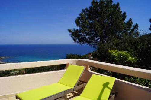 two green chairs sitting on a balcony overlooking the ocean at Domise in Conca