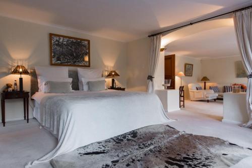 a bedroom with a large white bed and a living room at Kronendal Heritage in Hout Bay