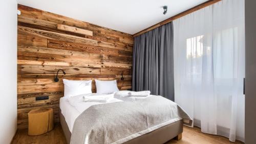 カルパチにあるDomki w Karpaczu SARNIA Sun & Snow - z Kominkamiの木のアクセントの壁とベッドが備わるベッドルーム1室が備わります。