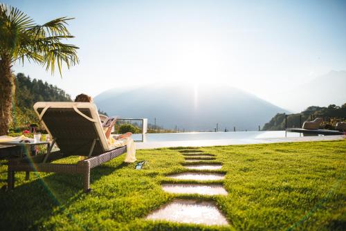 a woman sitting in a chair on a lawn at Hotel Kiendl in Schenna