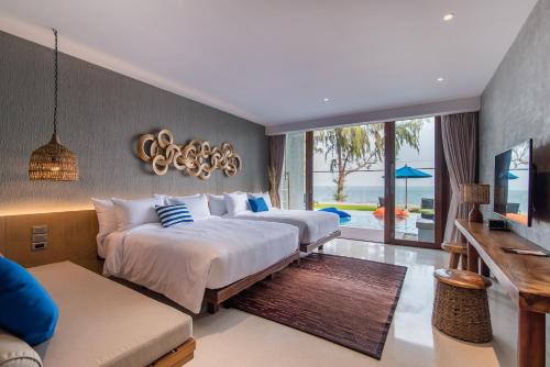 a hotel room with two beds and a tv at Lullaby The Sea Hua Hin in Cha Am