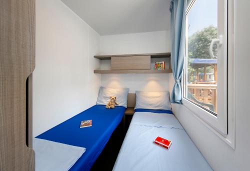 Habitación pequeña con 2 camas y ventana en Albatross Mobile Homes on Camping San Francesco, en Duna Verde