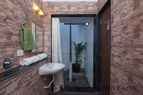 La salle de bains est pourvue d'un lavabo et d'un mur en briques. dans l'établissement Coconut Beach Farm, à Alibaug