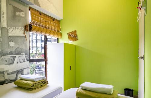 a green room with a bed and a window at PODs The Backpackers Home & Cafe, Kuala Lumpur in Kuala Lumpur