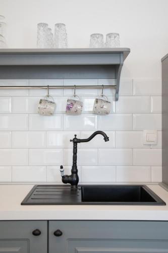 a kitchen sink with a black faucet and white tiles at Vila Alta in Selce