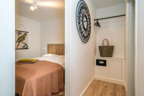a bedroom with a clock on the wall above the bed at De Herberg Appartementen in Renesse
