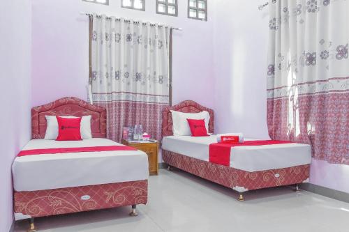 two beds in a room with red and white at RedDoorz Syariah @ Puri Kalijaga Street in Cirebon
