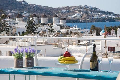 Mykonos Panorama with Private Terrace & Sea View في مدينة ميكونوس: طاولة عليها زجاجة من النبيذ والفواكه
