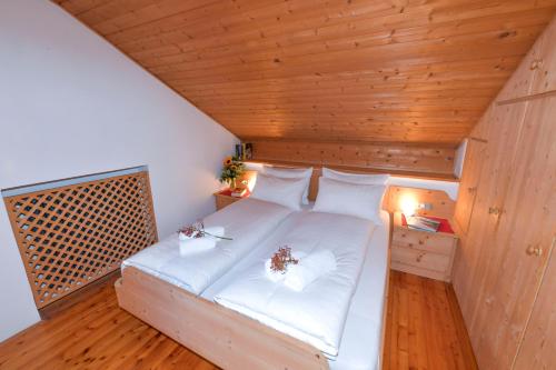 a bedroom with a bed with white sheets and flowers on it at Appartamenti Chedul in Selva di Val Gardena