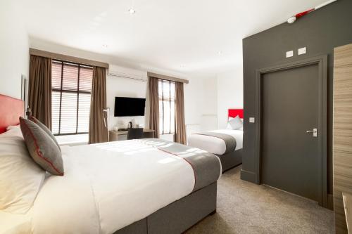 Habitación de hotel con 2 camas y TV en The Connaught Hotel Wolverhampton en Wolverhampton