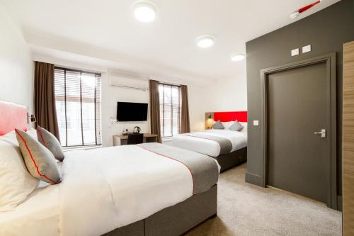 a hotel room with two beds and a television at The Connaught Hotel Wolverhampton in Wolverhampton