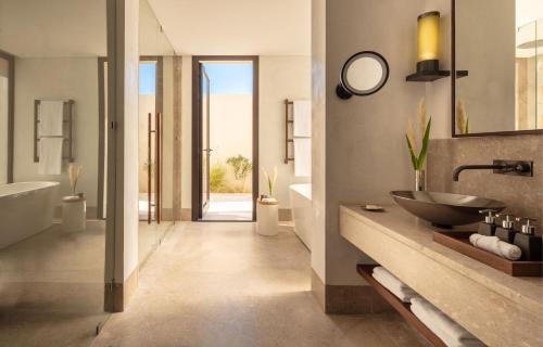 bagno con lavandino, vasca e specchio di Anantara Sahara-Tozeur Resort & Villas a Tozeur