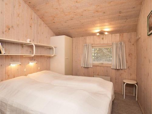 a bedroom with a white bed and a window at Simplistic Holiday Home in Jutland with Swimming Pool in Løkken